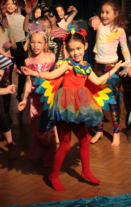 Year 3 girl dressed as a parrot dancing during 'Pirates Verus Mermaids' performance.