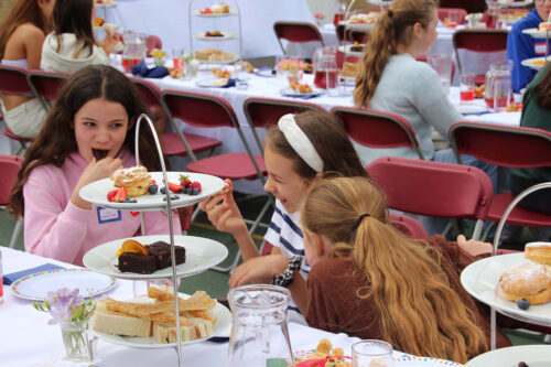 Girls at Alumnae Afternoon Tea eating cakes and talking to each other.