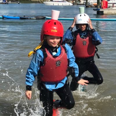 Two Year 5 girls balancing cups on their heads during water activity.