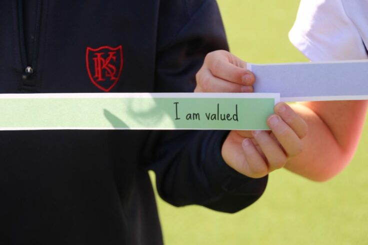 Girl holding piece of paper that says 'I am valued.'