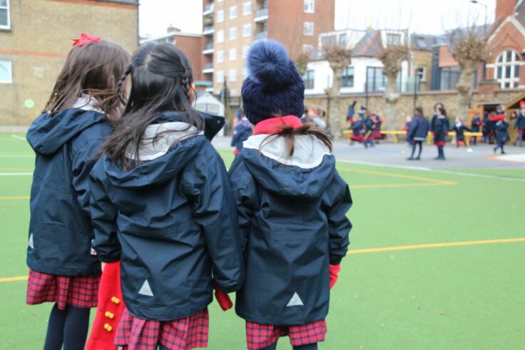 Ken Prep girls stood with their backs to the camera looking out at the playground.