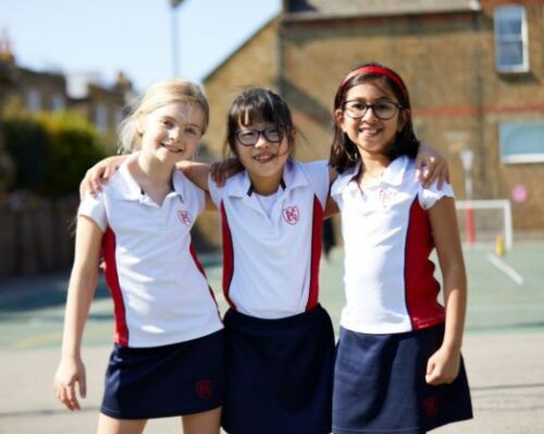 Three Ken Prep girls stood in the playground with their arms around each other.